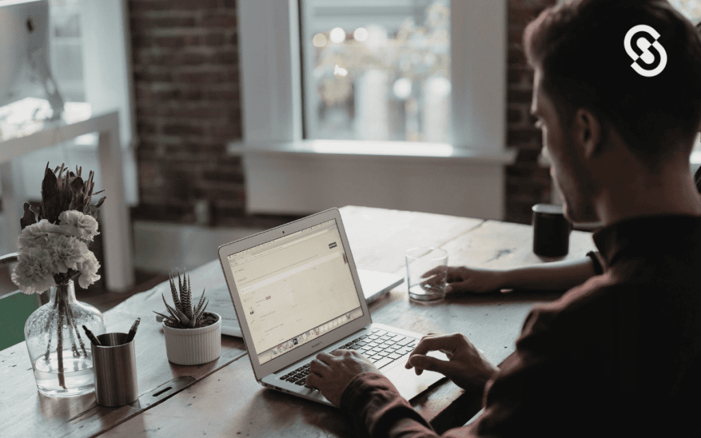 Persona trabajando en una computadora portátil en un espacio de trabajo iluminado, representando la atención al cliente por email profesional.