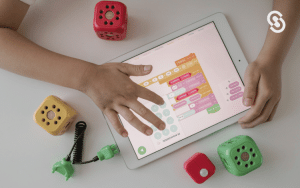 Niño interactuando con tablet y bloques de colores mientras usa un software educativo para aprender programación, ilustrando qué es un software educativo y cómo facilita el aprendizaje tecnológico