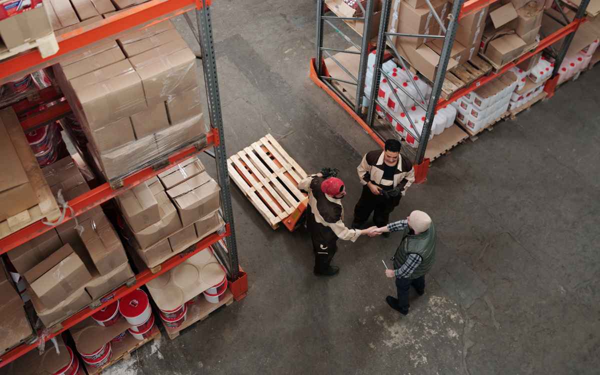 Vemos dos empleados y un cliente en un depósito negociando.