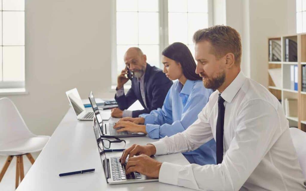 Vemos un equipo de personas trabajando frente a sus computadoras, cumpliendo con un servicio de outsourcing.