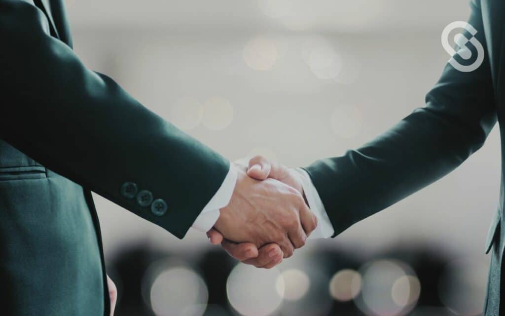 Dos personas estrechan su mano en una negociación