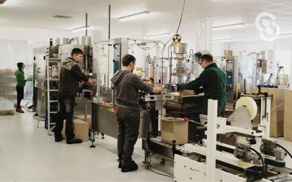 Vemos una imagen de obreros trabajando en una fárbica, en relación a los costos indirectos de fabricación.
