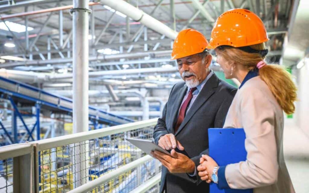 Vemos una imagen de dos personas de control de calidad en una fábrica durante la etapa de verificación del ciclo PDCA.
