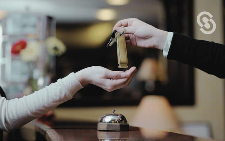 Vemos una imagen de un encargado entregando la llave de una habitación a un cliente, en relación con la búsqueda de un ejemplo de un CRM en un hotel.