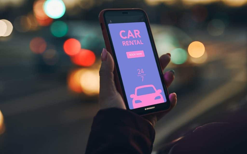 Smartphone mostrando una aplicación de alquiler de autos, ilustrando la digitalización de empresas de alquiler de autos y la conveniencia de reservar vehículos a través de plataformas digitales.