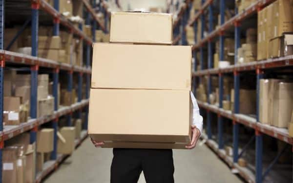 Persona llevando cajas de cartón en un depósito